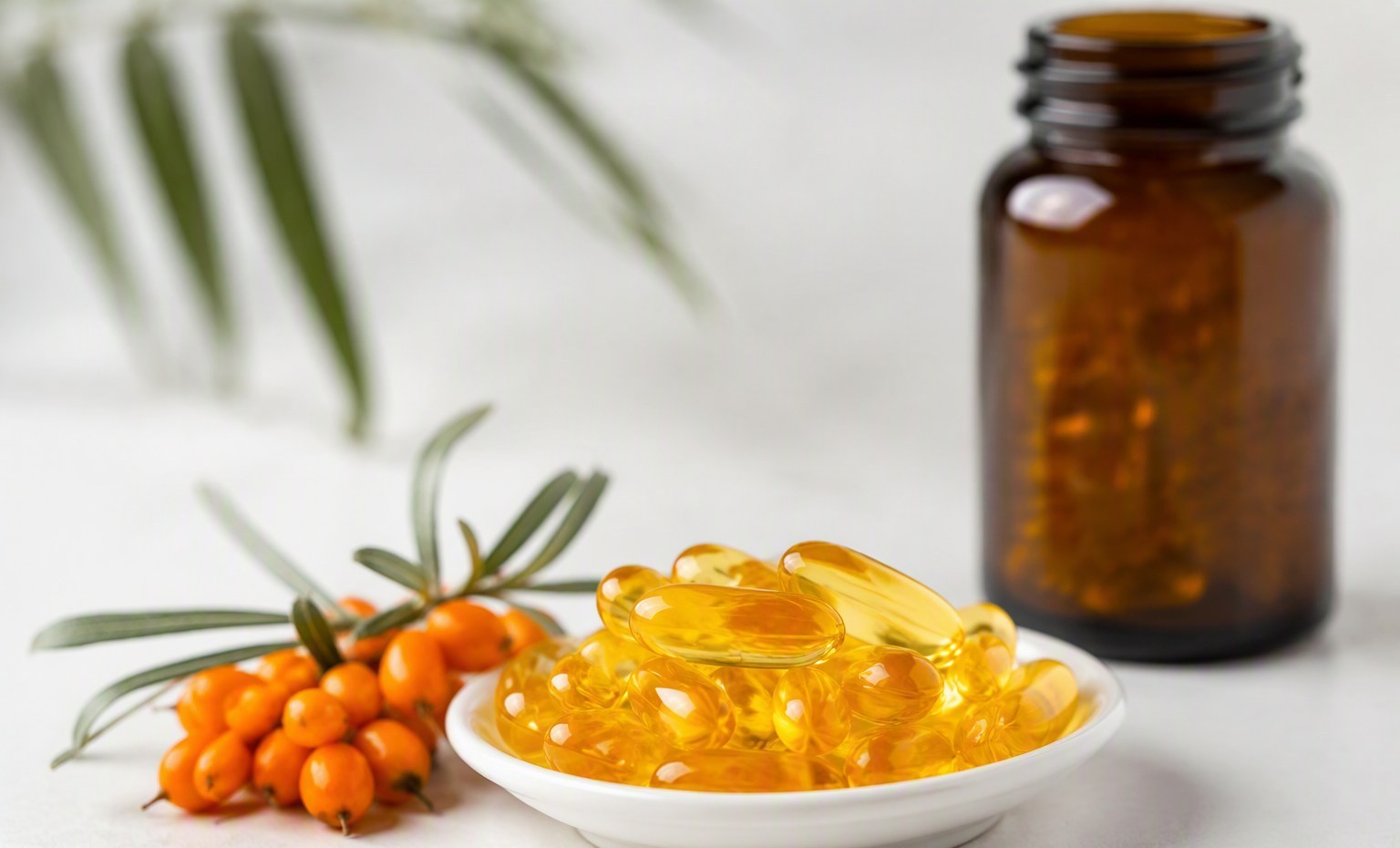Golden sea buckthorn softgel capsules in a small ceramic dish beside an amber bottle