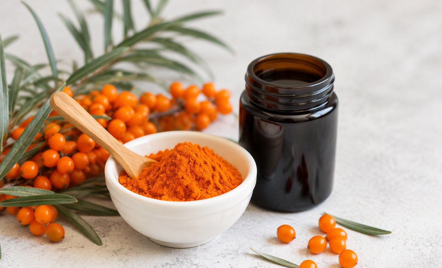 A small bowl of vivid orange sea buckthorn powder with a wooden spoon and dark glass jar